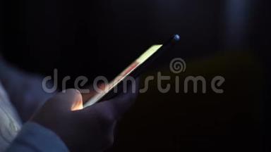女人的手在黑暗的房间里翻过手机的页面，特写。