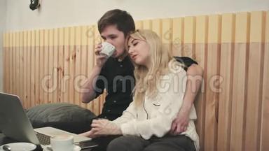 漂亮的年轻夫妇在咖啡馆里带着笔记本电脑，他们<strong>一起看电影</strong>和喝咖啡