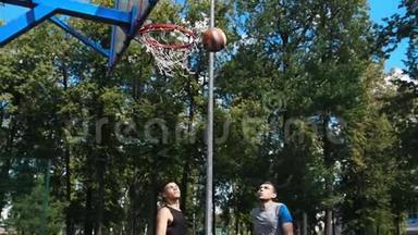 两个年轻人在户外打篮球-一个人扔球-另一个人得分