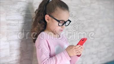 可爱的婴儿用手机或平板电脑娱乐。 小女孩把空闲时间花在玩手机游戏上，玩得很累