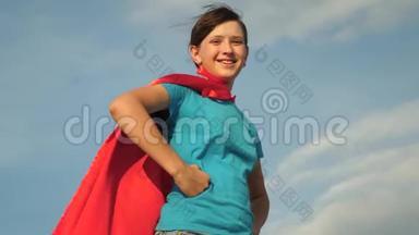 少女女超级英雄穿着红色<strong>斗篷</strong>站在田野上，<strong>斗篷</strong>随风飘扬。 慢动作。 特写镜头。 女孩的梦想