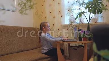 一个戴眼镜的小女孩用笔记本电脑工作或在上面玩。