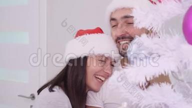 快乐的一对夫妇享受寒假时光，靠近圣诞树，微笑着拥抱。