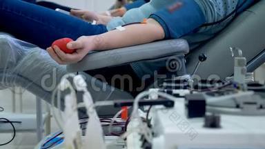 人们在诊所献血，坐在工作机器附近的椅子上。