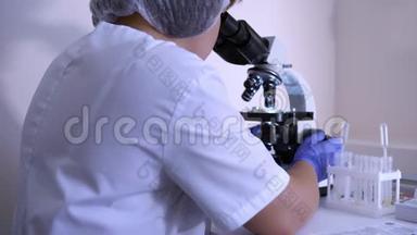 实验室里的女生物学家用显微镜工作