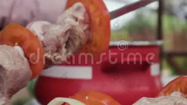 女人`手把猪肉、西红柿和洋葱放在镀铬烤架上