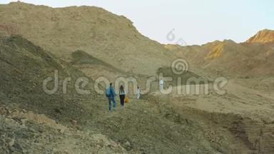 成群游客在炎热的沙漠中沿着岩石峡谷漫步，游客拍照留念，玩得开心.. 沙漠山脉