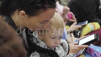 年轻的母亲和小儿子在乘<strong>地铁</strong>旅行时使用<strong>电话</strong>。