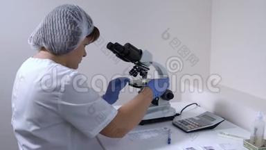 女实验室助理移动幻灯片并分析生物材料