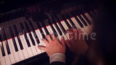 钢琴演奏者在钢琴上用低光线和肩部视野演奏一首歌