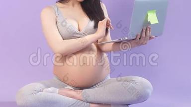 穿着瑜伽服的孕妇在笔记本电脑上上网。