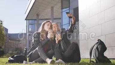 两个带着新鲜果汁的白种人少女坐在草坪上，用手机自拍，视频在户外聊天