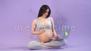 穿着瑜伽服的孕妇在笔记本电脑<strong>上上</strong>网。
