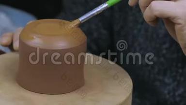 陶工用刷子给水壶上油，以固定<strong>盖子</strong>。 手工陶土茶壶，用于茶道。 棕色<strong>陶瓷</strong>茶壶。 4k