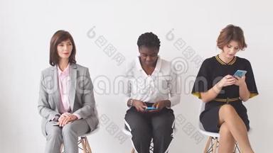 三个女商人希望在办公楼走廊的椅子上接受采访。