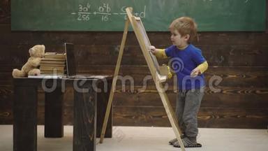 学前教育。 小男孩在黑板上画粉笔。 幼儿教育与游戏观念