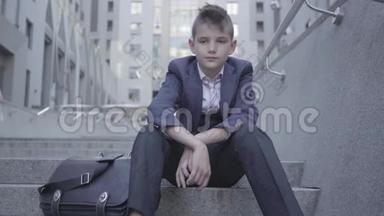 穿着考究的可爱男孩坐在街上的楼梯上。 这个男孩<strong>很累</strong>，想做个孩子。 儿童