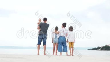 家庭旅行。 父母和三个穿着牛仔裤的<strong>孩子</strong>正在海边的白沙上休息，<strong>暑假</strong>