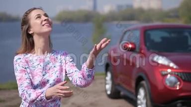 一个漂亮的女孩站在车前，扔钥匙，在车架上<strong>接住</strong>和挥动钥匙。 4K慢慢