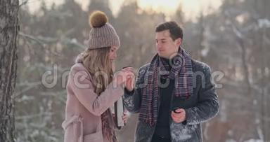 一个有爱心的男人在白雪覆盖的公园里的冬天温暖`妻子的双手