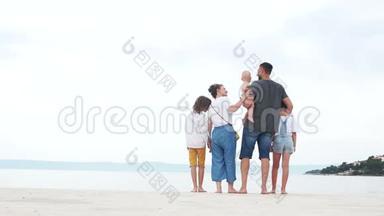一家五口抱着白沙在沙滩上.. 父母和三个孩子，家庭假期快乐