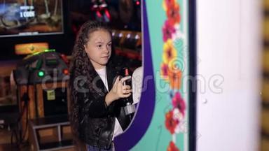 一个留着长长卷发的小女孩在现代儿童`房间里玩电子游戏