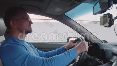 穿蓝色衬衫的白人驾驶汽车，在智能手机上观看视频。