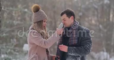 一个有爱心的男人在白雪覆盖的公园里的冬天温暖`妻子的双手