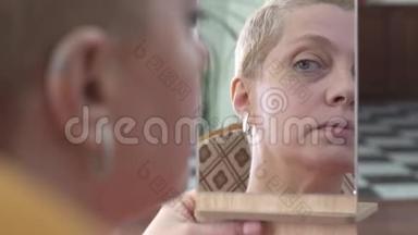 成年可爱的女人在看镜子的时候脸上涂面霜