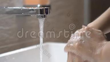 女人在浴室里用肥皂洗手。 把肥皂涂在手上。 泡沫的气泡。 慢动作。