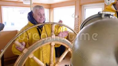在帆船上的船长桥上，一位老妇人转动方向盘。 成熟女船长掌舵漂浮