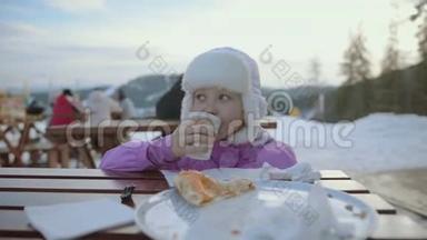 那个女孩正在吃午饭。 雪山中央的快乐女孩。 寒假。