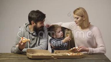 家人在交流，吃着美味的披萨.. 营养概念。 美味的披萨。 妈妈，爸爸和儿子在吃披萨