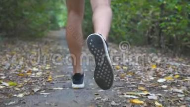 在初秋的森林里，一个运动的人沿着小径奔跑。 年轻运动员的男足沿着小路快速冲刺