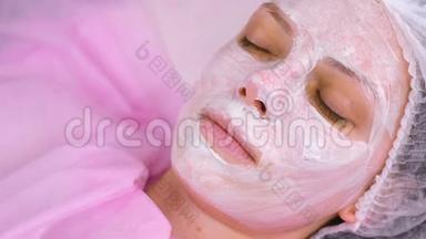 美容师用刷子把面具戴在女人`脸上。 滋润的脸。 面的特写..