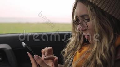 快乐的年轻女子在她的智能手机上，在红灯时停车的座位上，慢动作