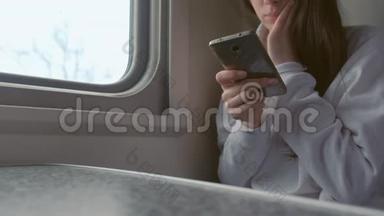 疲惫的年轻女子在火车上用手机看视频。 双手特写..