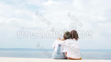 快乐的<strong>孩子</strong>们，一个男孩和一个女孩坐在海边拥抱，看着远处。 <strong>暑假</strong>旅行