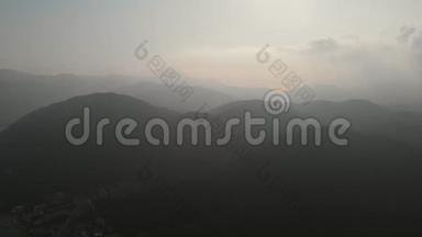 空中：飞越陡峭的小山，向群山飞去.. 镜头朝着雾蒙蒙的群山飞去.. 山里的雾