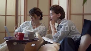 两个成年妇女<strong>一起</strong>在家里喝茶或喝咖啡，<strong>一起</strong>在笔记本电脑上<strong>看电影</strong>。 两个优雅成熟的女朋友