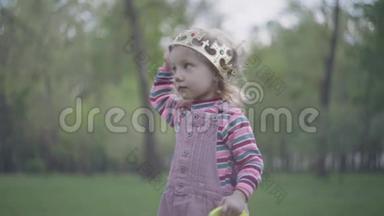 可爱的小女孩在她的<strong>皇冠</strong>上的前景，绿色公园的背景。 <strong>皇冠</strong>太大了