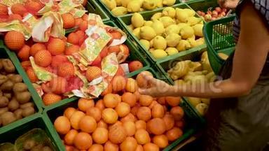 女手在超市里摘橘子。 女人从超市的盒子里拿水果