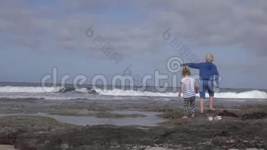 一个小女孩和她哥哥正在海边的海滩上玩耍