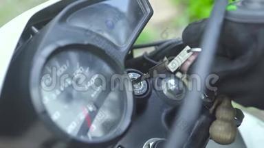 摩托车手插入键启动摩托车发动机。 关闭摩托摩托车启动摩托车驾驶。