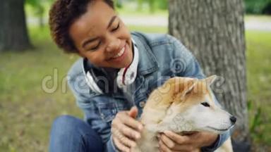 可爱的非裔美国女孩宠物主人抚摸着它的狗，在它的脖子上抚摸着它的皮毛，看着动物的缓慢动作