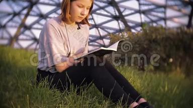 阳光明媚的一天，穿着t恤坐在公园草地上读讲稿的年轻少女