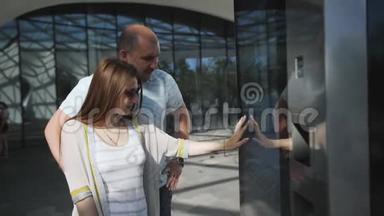 夫妇站在现代建筑中，使用电子信息板站在街上。 <strong>交互式</strong>屏幕