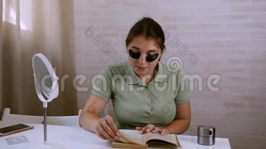 一个年轻的女人，眼睛下面有一个黑色的眼罩，读一本书，用计时器。 <strong>美容护肤</strong>