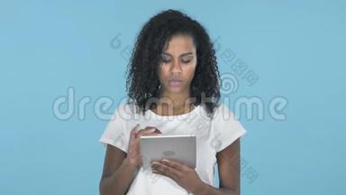 非洲女孩在<strong>蓝色</strong>背景下使用平板电脑时浏览<strong>互联网</strong>