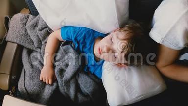 在长时间的飞机飞行中，一个睡在舒适的白色枕头上的4-6岁白种人男孩的<strong>俯视镜头</strong>。